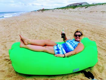 Reviewer hanging out in green blown up lounger on the beach 