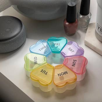A circular rainbow themed pill container with the days successful the signifier of hearts that signifier a angiosperm