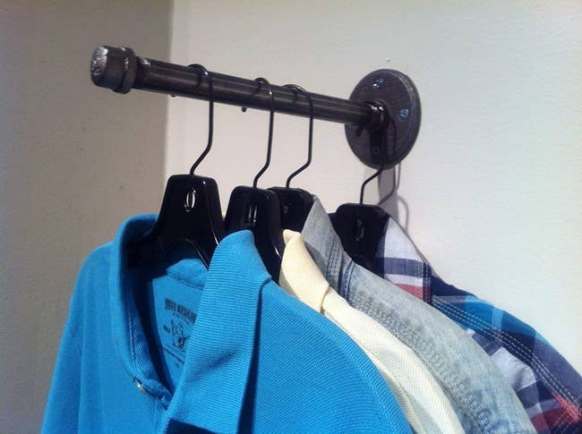 wall mounted rod with several shirts on a hanger on it