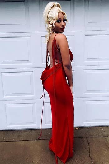 Reviewer posing in front of a garage door wearing the dress in small red