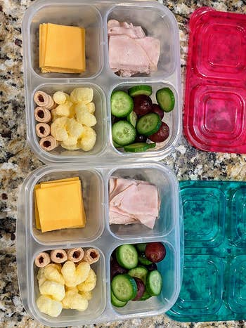 a reviewer photo of two snack boxes filled cheese, meat, veggies, and puff snacks