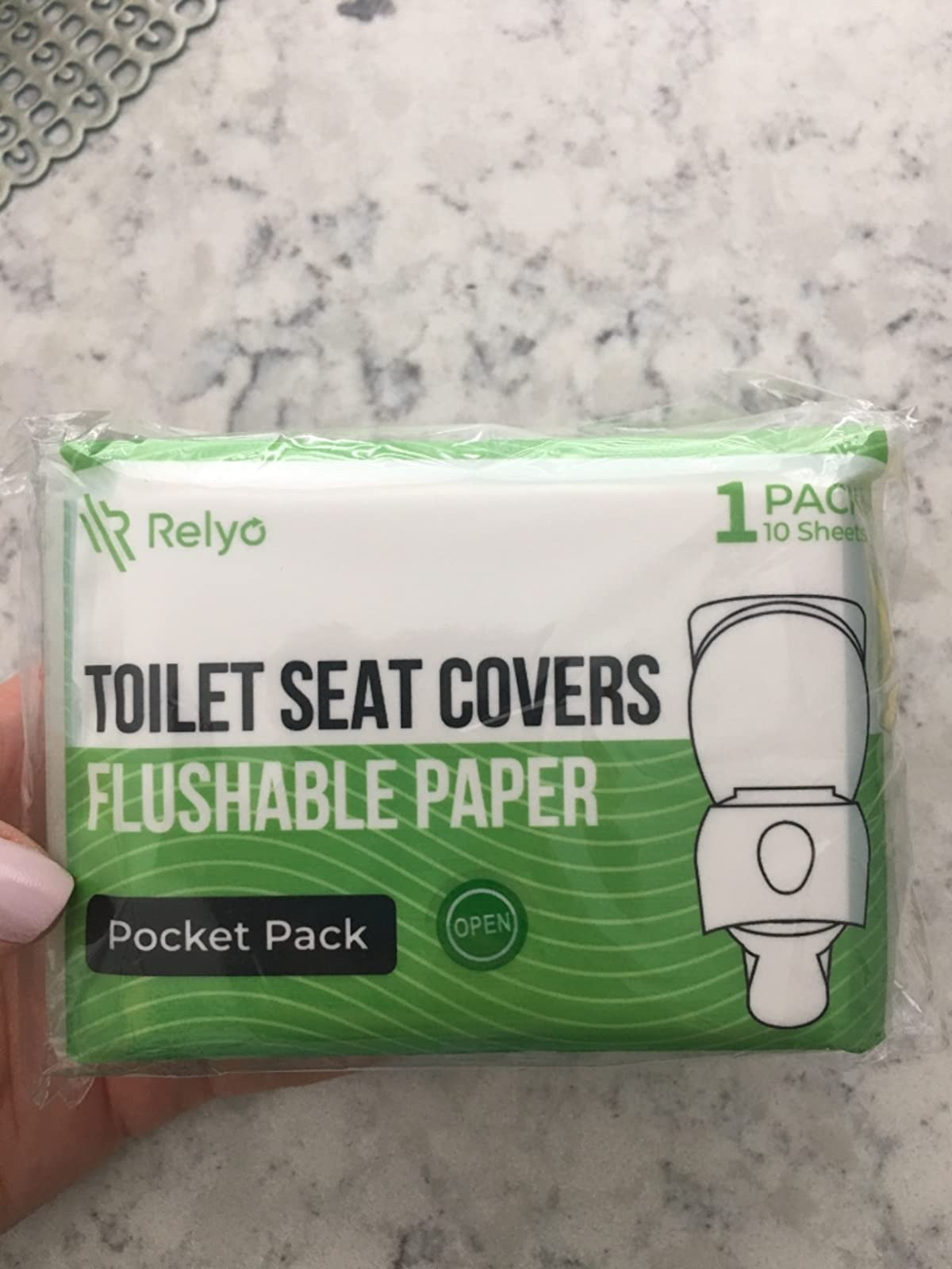 image of reviewer's manus  holding up   battalion  of flushable toilet spot   covers