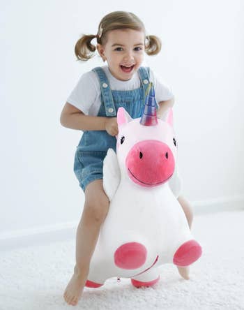 Child riding a unicorn-shaped artifact  with a large  smile, wearing overalls and a achromatic  shirt, perfect  for playful indoor fun