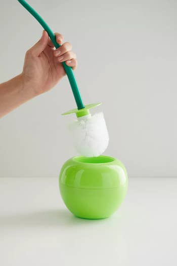 model holding green apple-shaped toilet brush