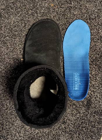 Reviewer's boot beside blue removed insole on a carpet