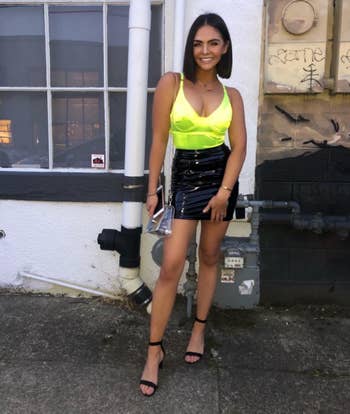 reviewer wearing neon green color with a leather skirt and black pumps