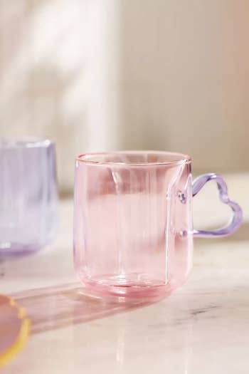 a pink glass mug with a heart-shaped purple handle