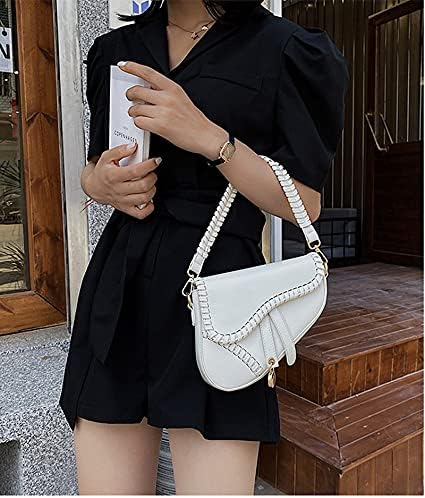 Person wearing a stylish black dress holds a white designer handbag