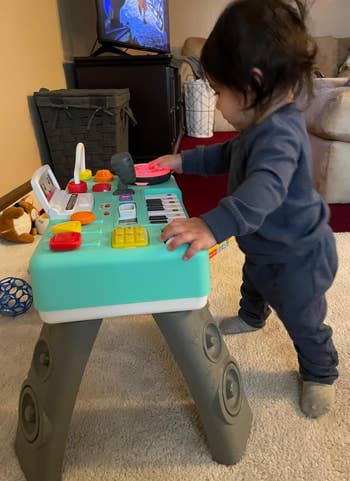 a toddler standing at a DJ kids turntable set