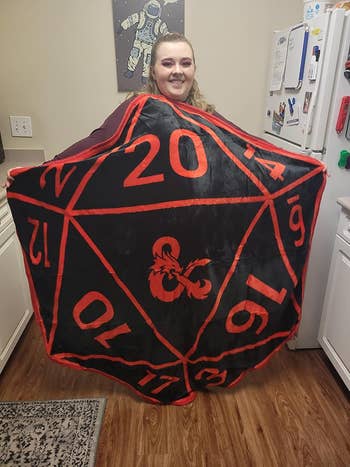 Person holding a large 20-sided die costume with a fleur-de-lis symbol