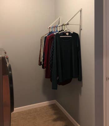 the rack with a large bar in the middle with hanging cardigans in laundry room