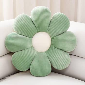 the green flower-shaped pillow on a couch