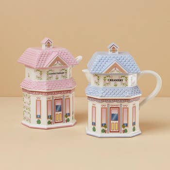 Two cottage-shaped ceramic teapots, one labeled 