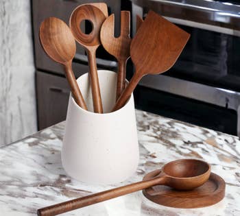 Wooden spoons and spatulas in a white holder, placed on a kitchen countertop
