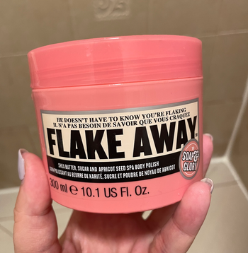 a buzzfeeder holding the pink jar of exfoliator
