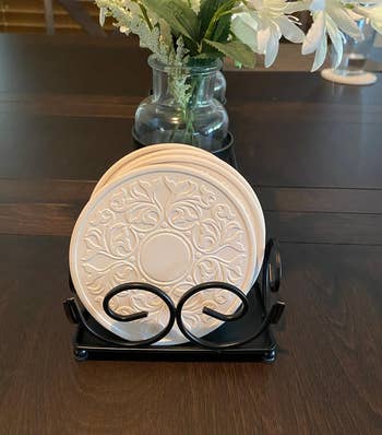 lace-carved white round stone coasters in a black holder 