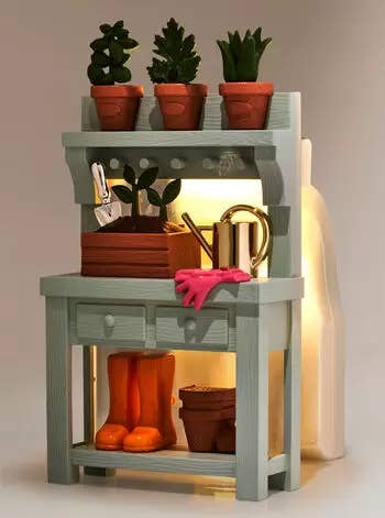 A minimalist wooden shelving unit with plants, gardening tools, a watering can, and a pair of boots. Ideal for home organization
