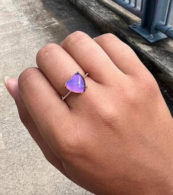 A hand wearing a heart-shaped purple gemstone ring. The article is categorized as Shopping