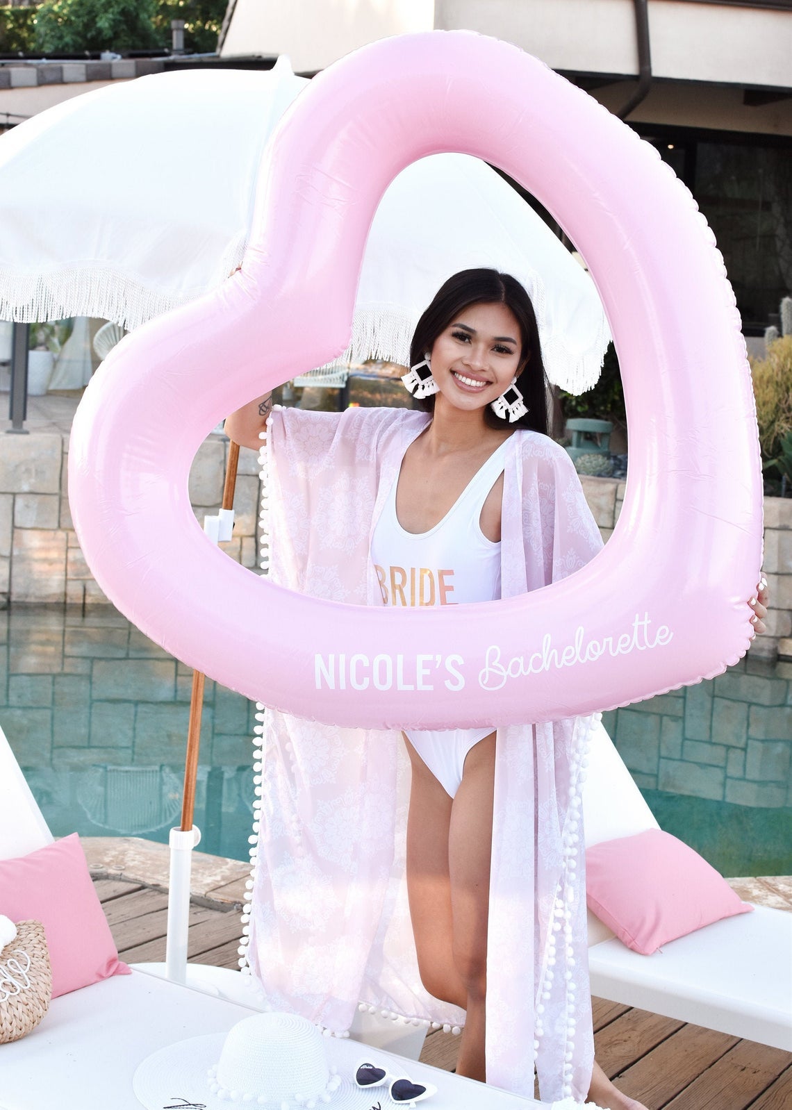 model holding up pink heart shaped tube with white letters reading