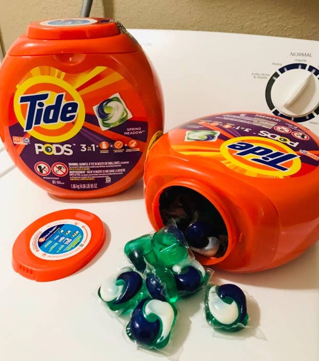 two tide pod containers on reviewer's washing machine. one is tipped over with pods falling out to show product.