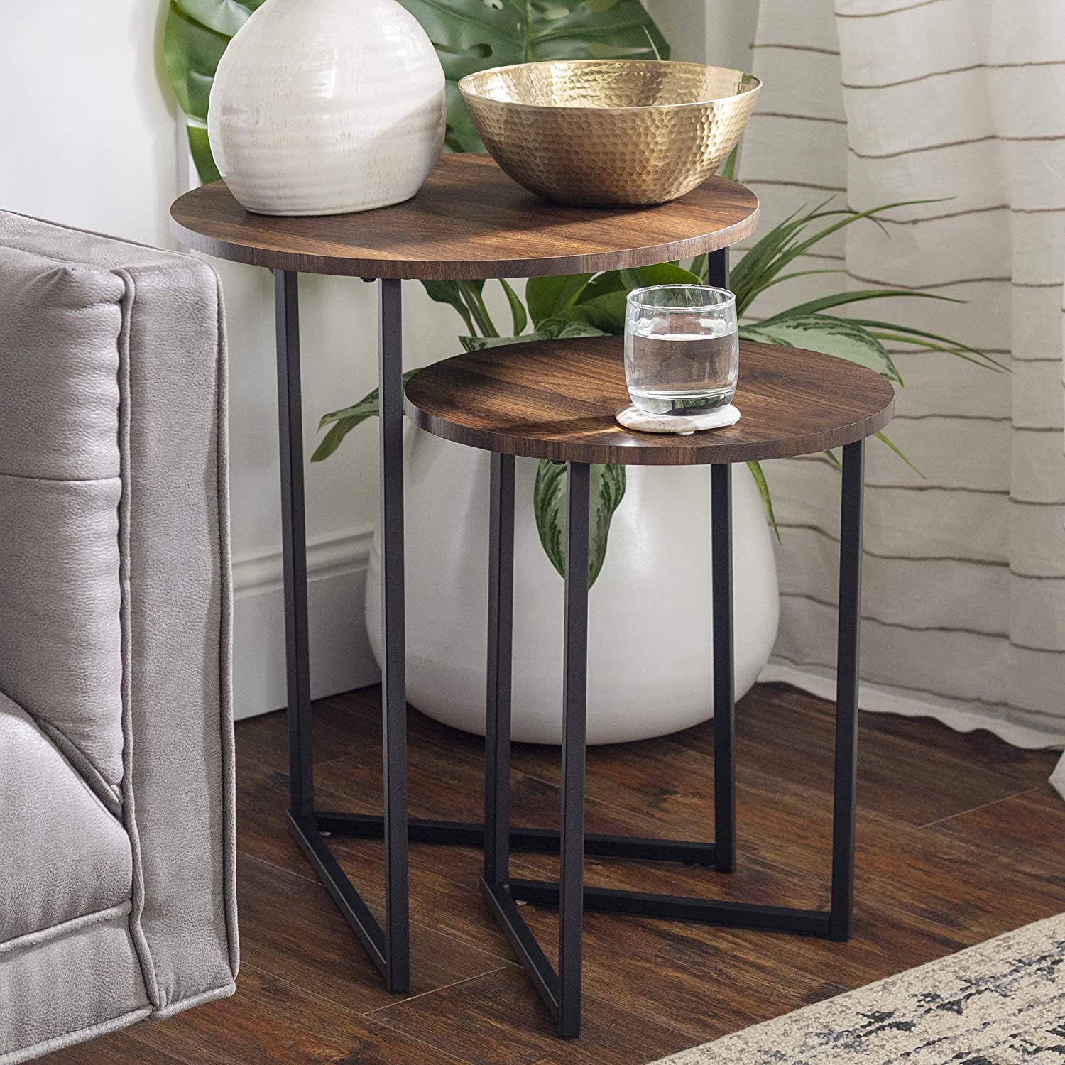 the two nesting tables holding a glass of water, bowl, and vase
