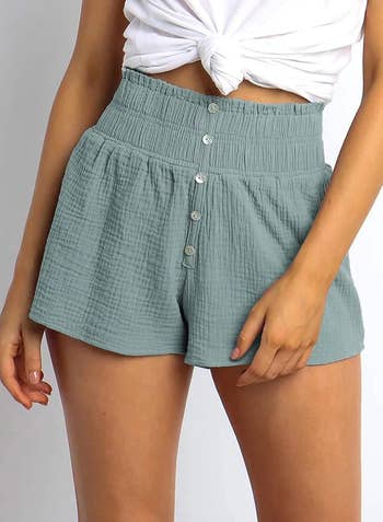 model in green shorts with button detail