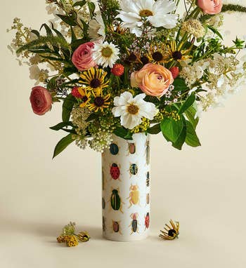 Vibrant floral statement successful a decorative vase with insect patterns, featuring roses, daisies, and wildflowers. Perfect for location decor shopping