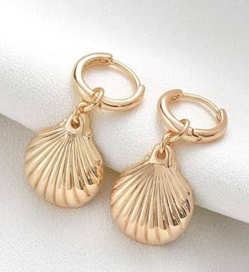 Gold seashell-shaped earrings displayed on a white background