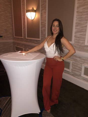Person successful a sleeveless apical and wide-leg pants stands by a gangly array successful an indoor setting