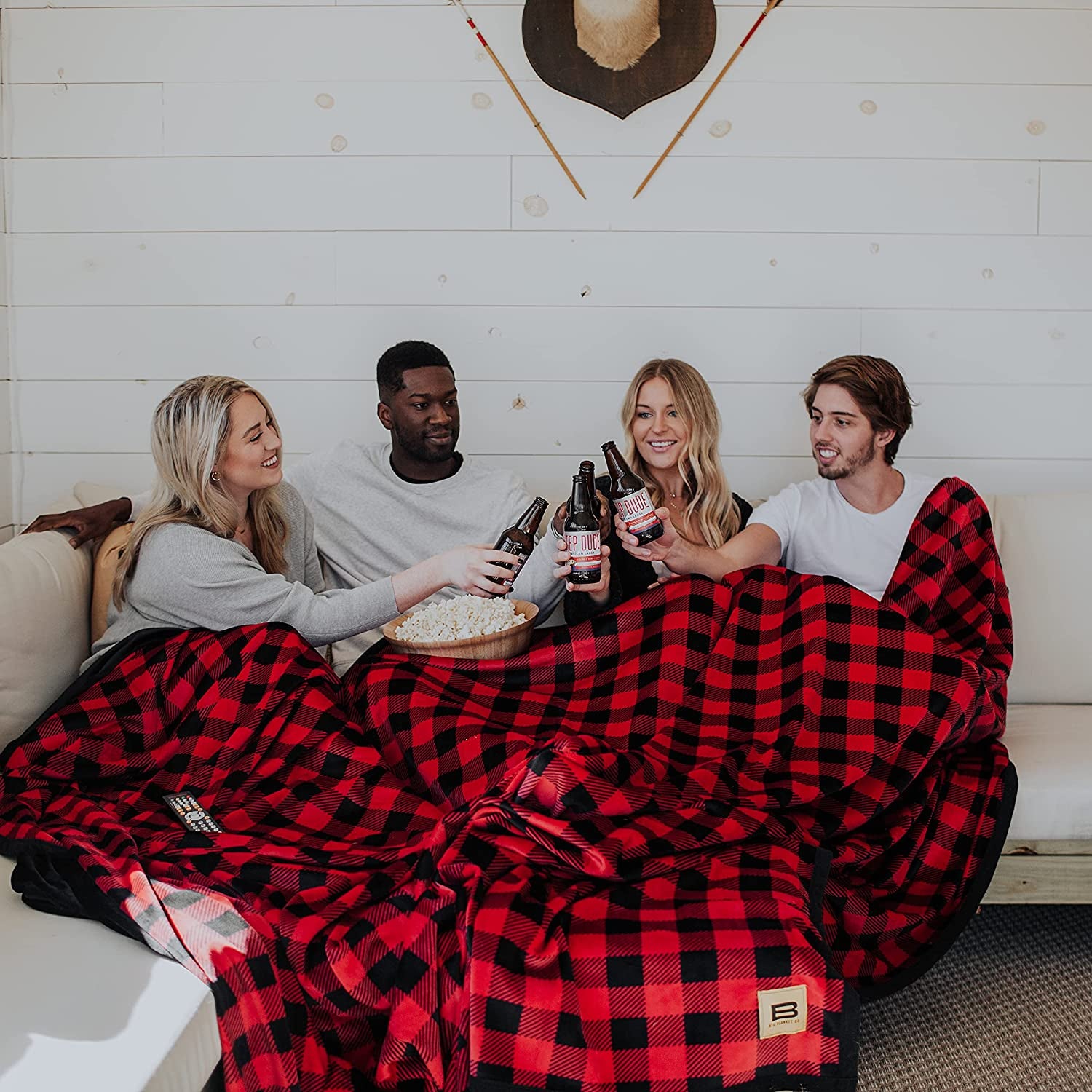 Four people inside a very large black and red checkered blanket