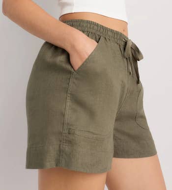 Person wearing casual linen shorts with an elastic waistband and pockets, suitable for a relaxed, mundane style