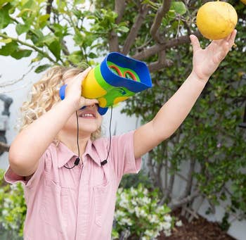 Child utilizing colorful binoculars to scope for a effect connected a histrion branch