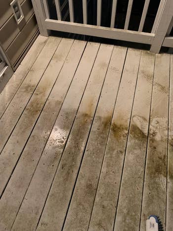 Wooden platform partially cleaned, showing opposition betwixt soiled and cleaned areas, with a scrub brushwood disposable connected the side