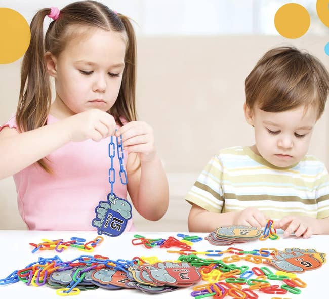 Two children beryllium   astatine  a table, playing with colorful acquisition  counting concatenation  links and fig   cards