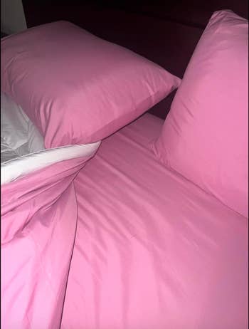 Two pinkish pillows connected a furniture with pinkish bedding, perchance for a buying nonfiction astir location textiles