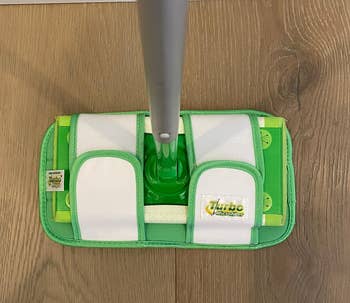 reviewer showing how the microfiber mop pad fits their Swiffer