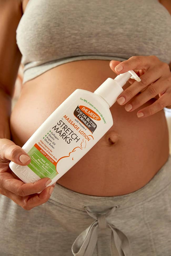 Pregnant person holding stretch mark lotion 