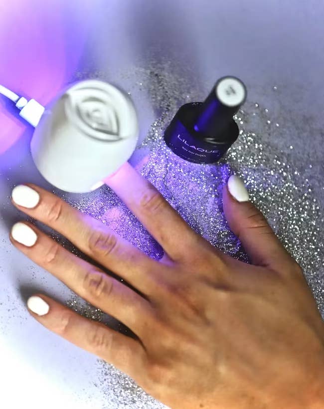 person curing nail polish with UV light