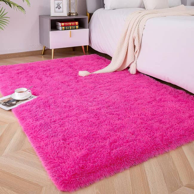 the pink fluffy rug in a bedroom next to a bed and nightstand 