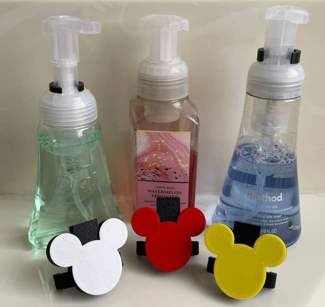 Three bottles of soap with Mickey Mouse shaped attachments 