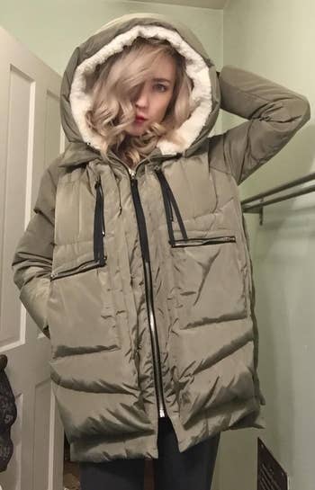 Person posing successful a puffy overgarment with a fur-lined hood, lasting indoors, manus connected hood, suitable for acold upwind buying enthusiasts