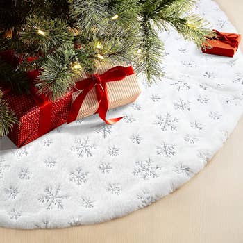 a white plush faux fur tree skirt with silver snowflakes on it