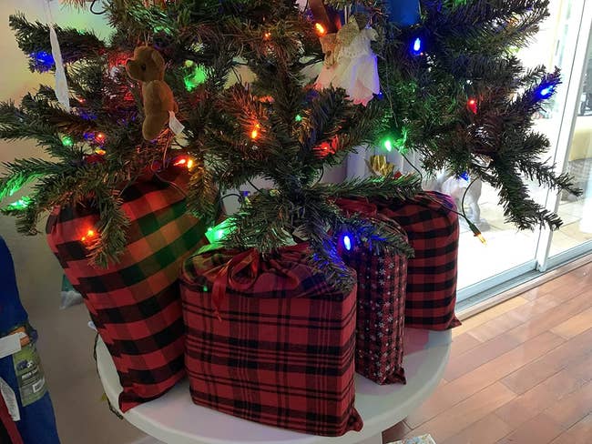 a reviewer photo of the filled bags sitting under aa tabletop Christmas tree 