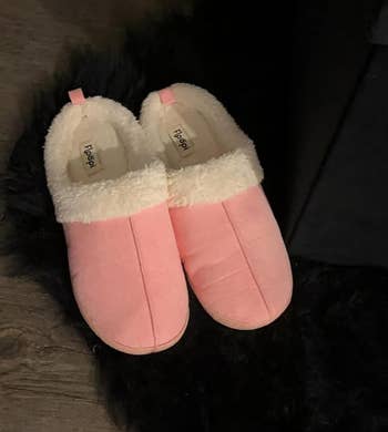 Pink slippers with fluffy lining on a dark background