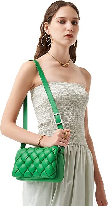 model carrying kelly green puffy woven bag with long shoulder strap