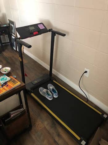 reviewer photo of a black treadmill with a pair of sneakers on it