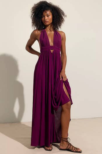 Person wearing a sleeveless, halter-neck maxi dress with side slit, posing in strappy sandals. The dress is elegant, suitable for an evening event