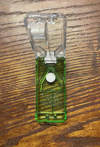 a reviewer photo of the pill cutter open with a whole pill inside 