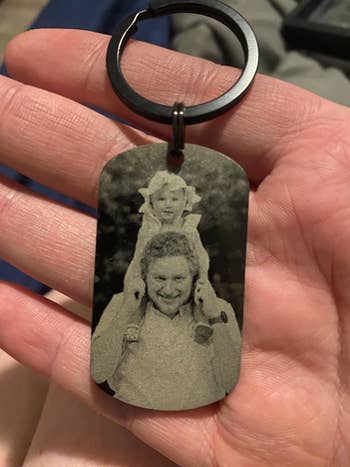 Keychain showing engraved photograph  of a smiling big  with a kid  connected  their shoulders