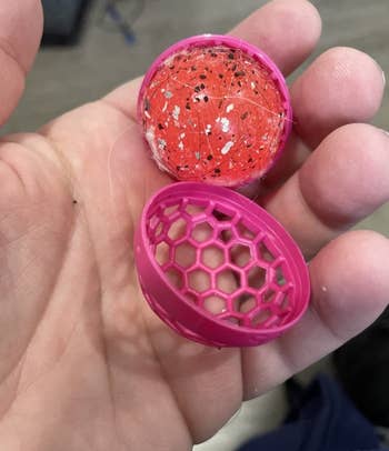 image of reviewer holding the pink ball open to reveal the sticky insert inside is covered in crumbs and hair